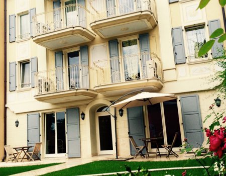 Residence facade with balconies and garden.